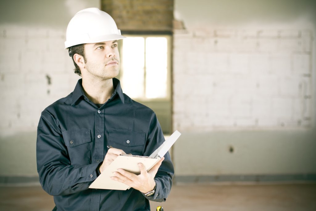 Un travailleur inspecte un bâtiment en prenant des notes